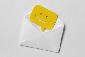 Email envelope with smiling message bubble on white background.