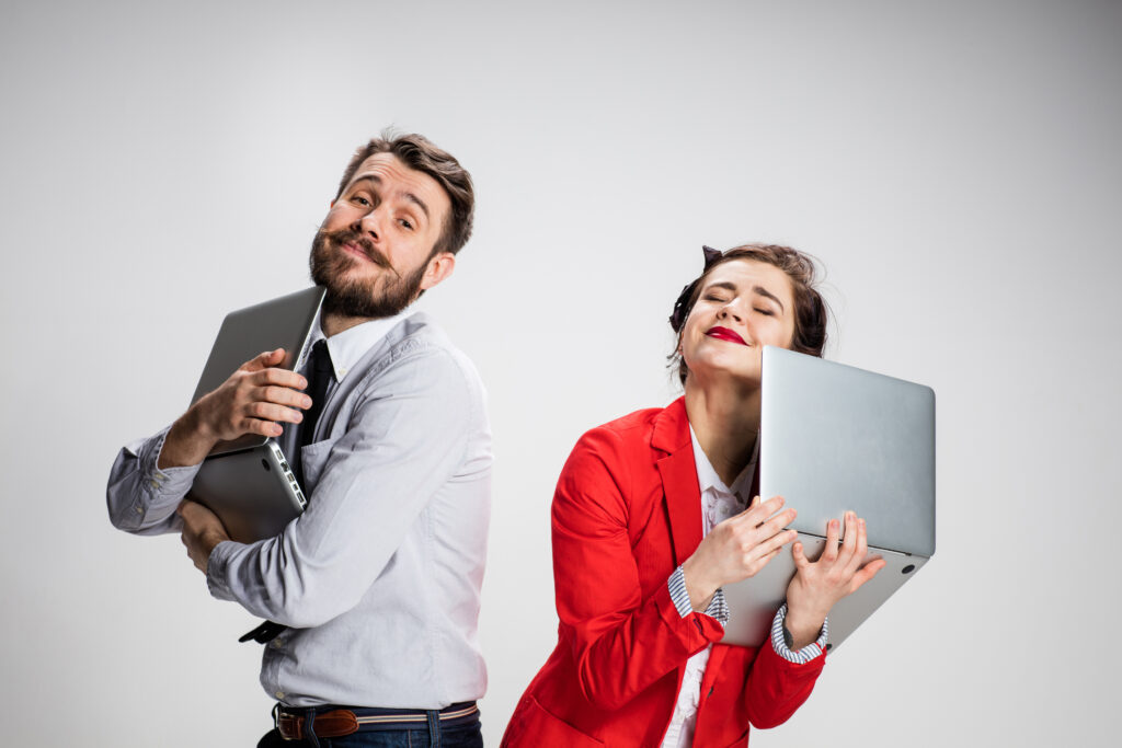 Email sign-off concept: A marketer and lead each embrace their laptops after receiving emails from one another.
