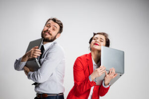 Email sign-off concept: A marketer and lead each embrace their laptops after receiving emails from one another.