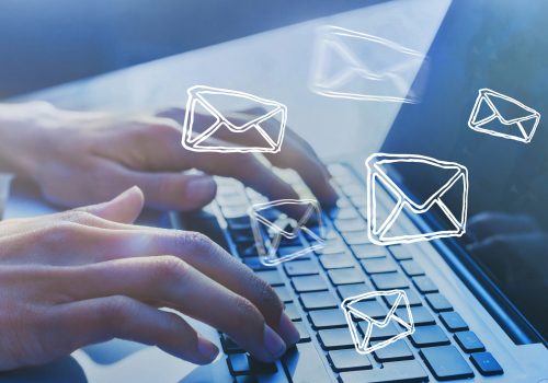 Prospecting Email Hands type on a laptop keyboard while images of emails float through the air.