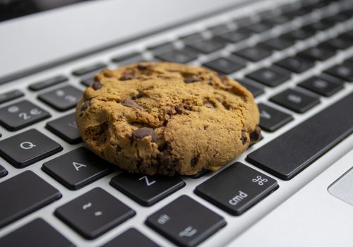 Website Cookie A chocolate chip cookie rests on a computer keyboard.